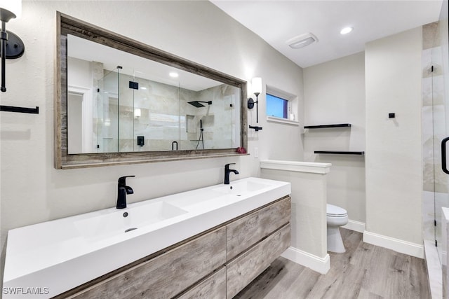 bathroom with hardwood / wood-style flooring, toilet, walk in shower, and vanity