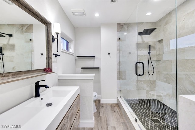 bathroom featuring toilet, wood-type flooring, a shower with door, and vanity