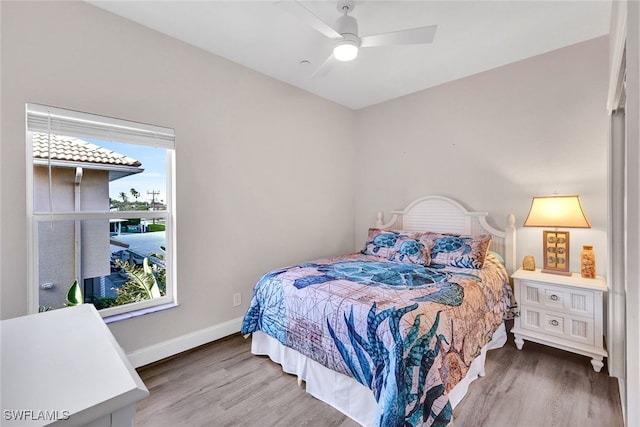 bedroom featuring ceiling fan, wood-type flooring, and multiple windows