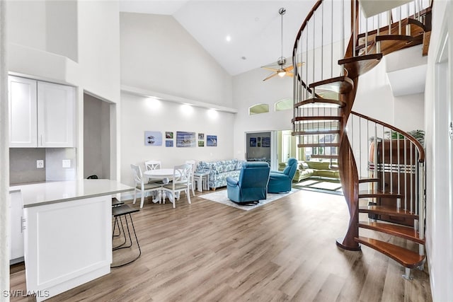 living room featuring ceiling fan, light hardwood / wood-style floors, and high vaulted ceiling