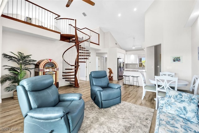 living room featuring light wood-type flooring, ceiling fan, and high vaulted ceiling