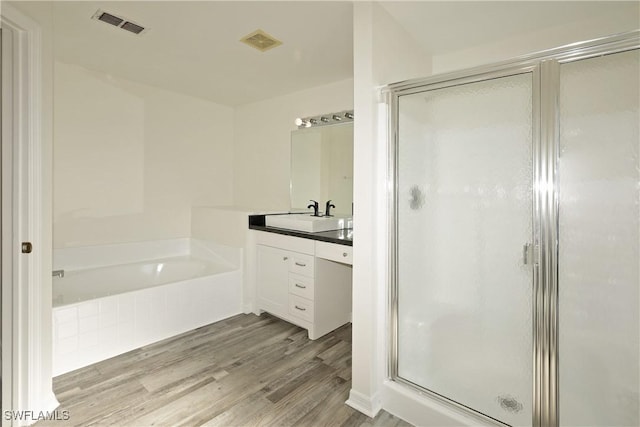 bathroom featuring hardwood / wood-style flooring, vanity, and shower with separate bathtub