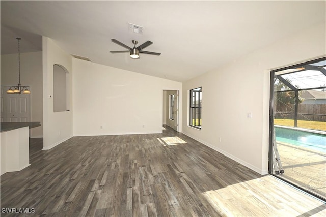 unfurnished living room featuring ceiling fan with notable chandelier, dark hardwood / wood-style flooring, lofted ceiling, and a wealth of natural light