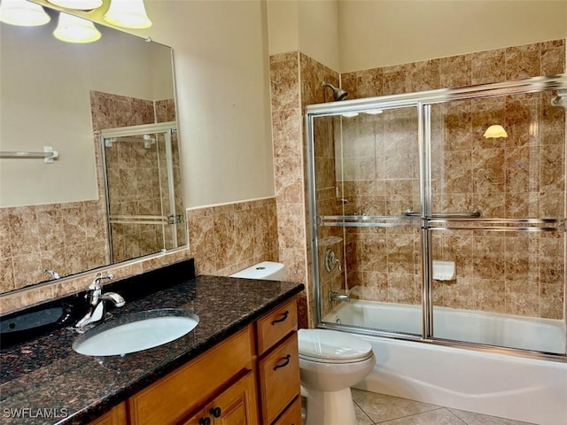 full bathroom featuring vanity, tile walls, enclosed tub / shower combo, tile patterned flooring, and toilet