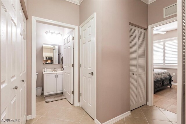 corridor featuring light tile patterned floors, ornamental molding, and sink