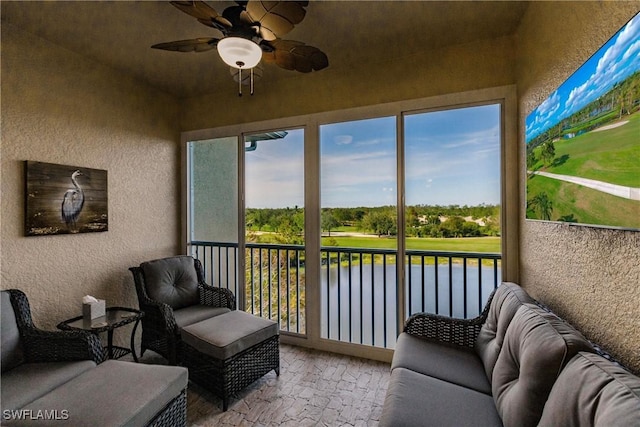 sunroom featuring ceiling fan and a water view