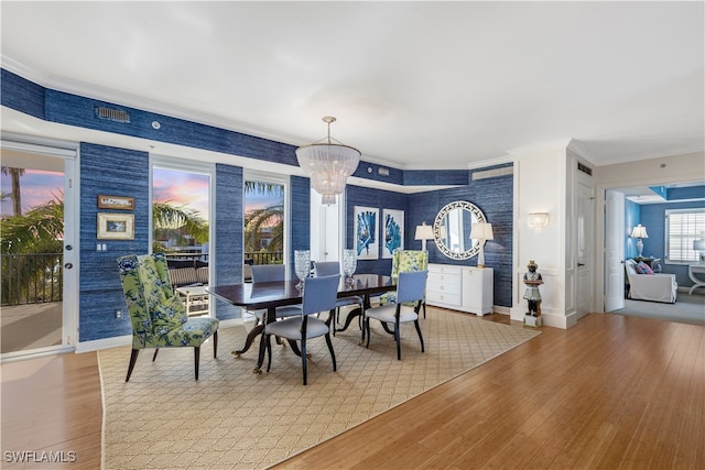 dining room with baseboards, a notable chandelier, wood finished floors, and ornamental molding