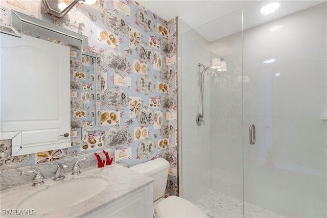 bathroom with a shower stall, wallpapered walls, vanity, and toilet