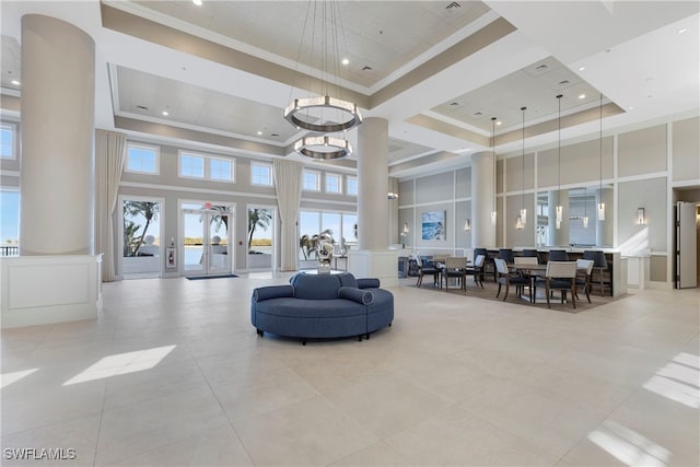 living area with decorative columns, a towering ceiling, crown molding, and a decorative wall