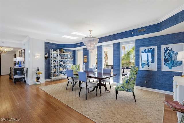 dining space featuring a notable chandelier, wallpapered walls, baseboards, and hardwood / wood-style floors