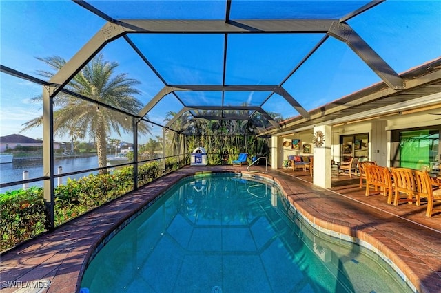 view of swimming pool with glass enclosure, a patio area, and a water view