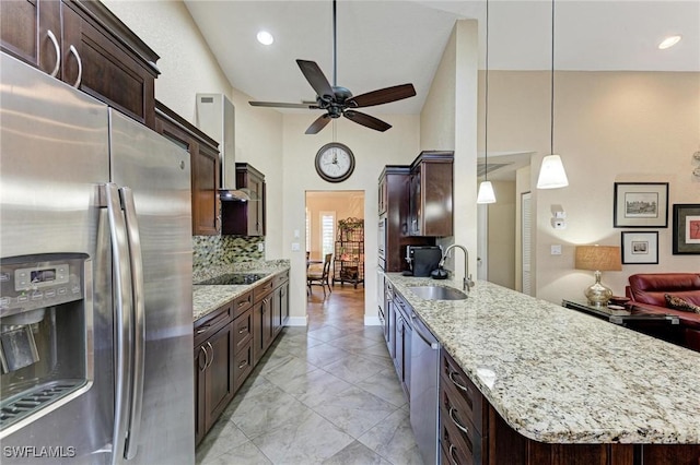 kitchen with appliances with stainless steel finishes, tasteful backsplash, wall chimney exhaust hood, sink, and hanging light fixtures