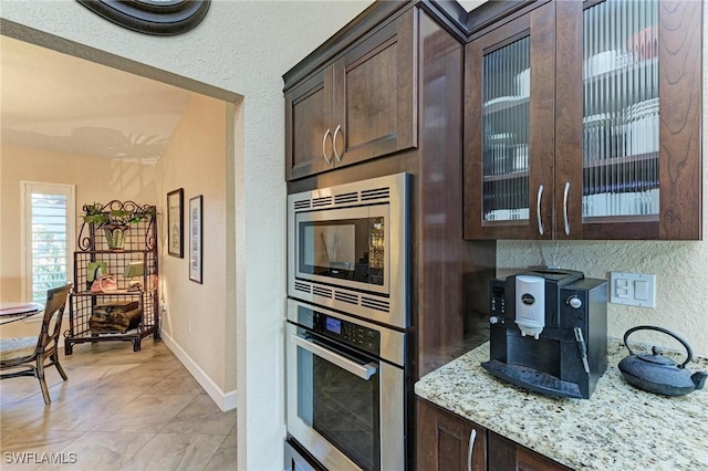 kitchen with appliances with stainless steel finishes, dark brown cabinetry, and light stone counters