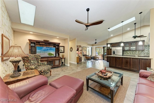 living room with a skylight, high vaulted ceiling, ceiling fan, and sink