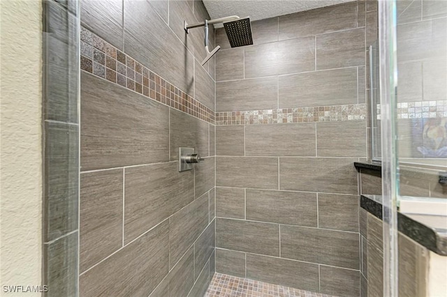 bathroom with a textured ceiling and tiled shower