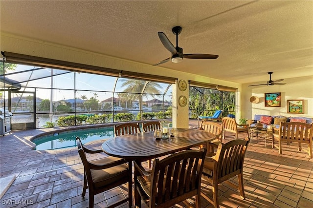 view of patio / terrace featuring glass enclosure, ceiling fan, a water view, and an outdoor hangout area