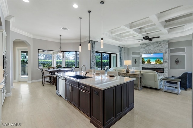 kitchen with light stone countertops, sink, a center island with sink, a fireplace, and white cabinetry