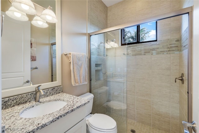 bathroom with an enclosed shower, vanity, and toilet