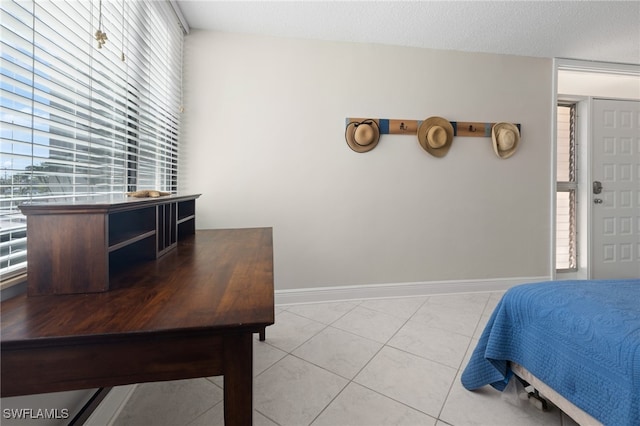 bedroom with light tile patterned floors, a textured ceiling, and baseboards