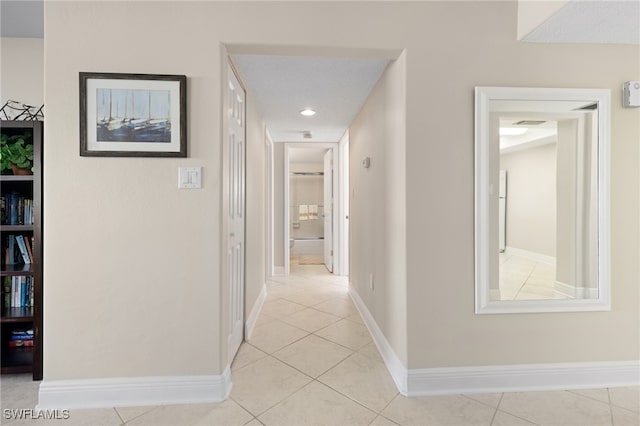 corridor featuring baseboards and light tile patterned floors