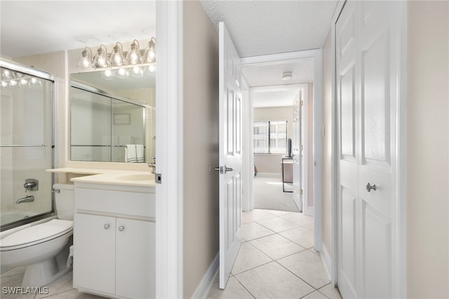 bathroom featuring a textured ceiling, tile patterned flooring, toilet, vanity, and combined bath / shower with glass door