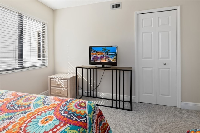 carpeted bedroom featuring a closet, visible vents, and baseboards