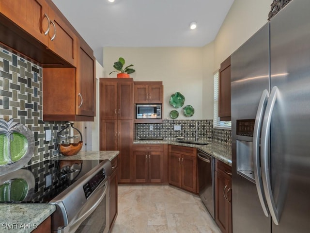 kitchen featuring stainless steel appliances, light stone counters, tasteful backsplash, and sink