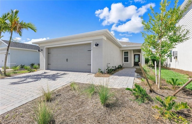 ranch-style home featuring a garage, decorative driveway, and stucco siding