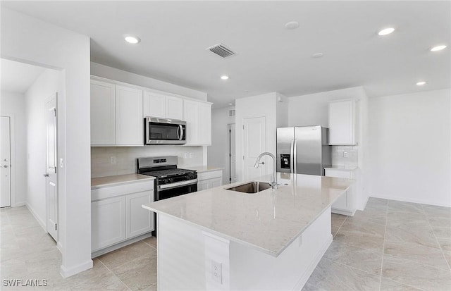 kitchen featuring a sink, visible vents, white cabinets, appliances with stainless steel finishes, and a center island with sink