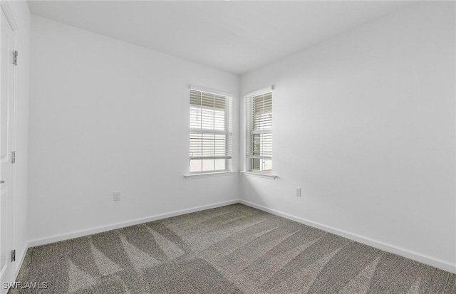 empty room featuring carpet and baseboards