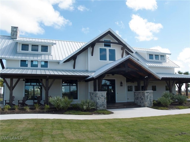 view of front of house with a front yard, a standing seam roof, metal roof, and a chimney