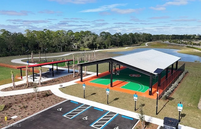 view of home's community with uncovered parking, community basketball court, and a water view