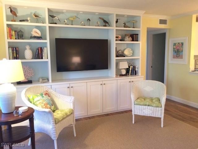 living area with crown molding and light wood-type flooring