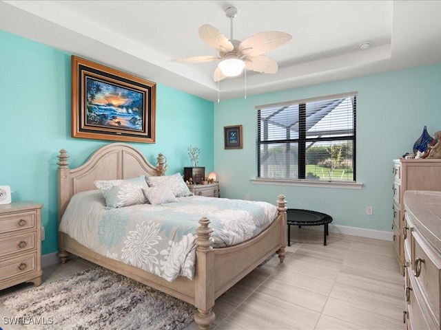 bedroom with ceiling fan, light tile patterned flooring, and a raised ceiling