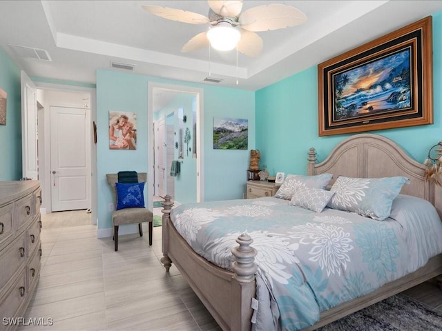 bedroom with ceiling fan, connected bathroom, and a tray ceiling