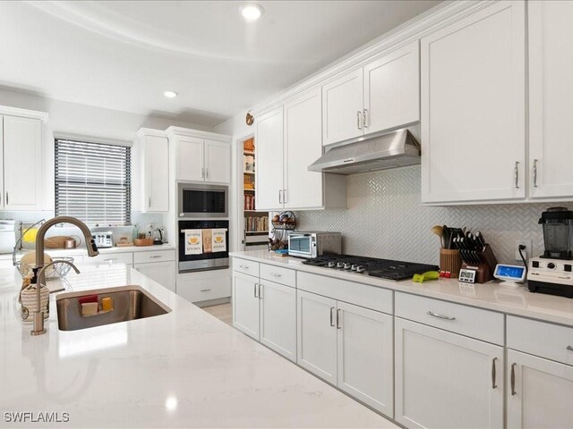 kitchen with white cabinets, decorative backsplash, stainless steel appliances, and sink