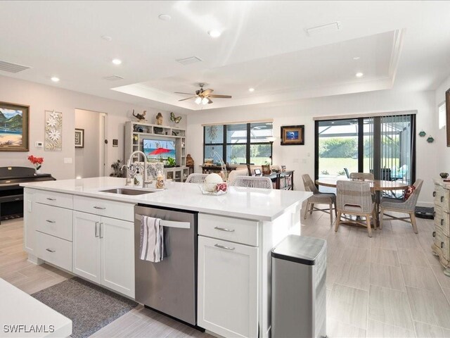 kitchen with a raised ceiling, white cabinetry, sink, and stainless steel dishwasher