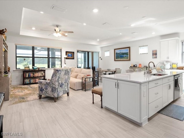 kitchen featuring white cabinetry, sink, dishwasher, a raised ceiling, and a kitchen island with sink