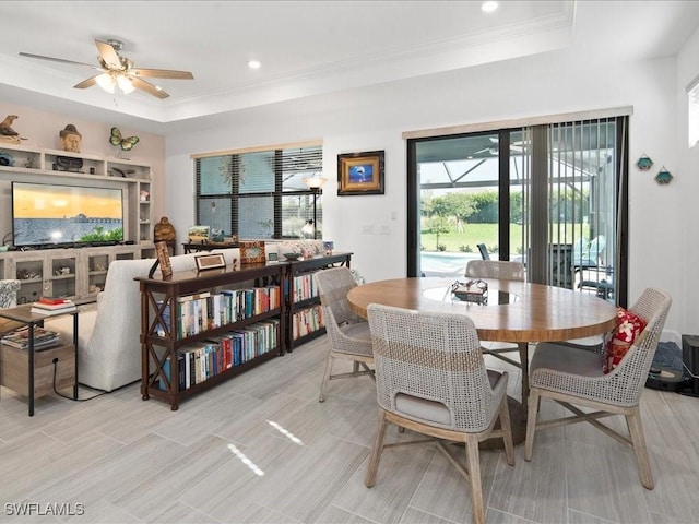 dining area with a tray ceiling, ceiling fan, and crown molding