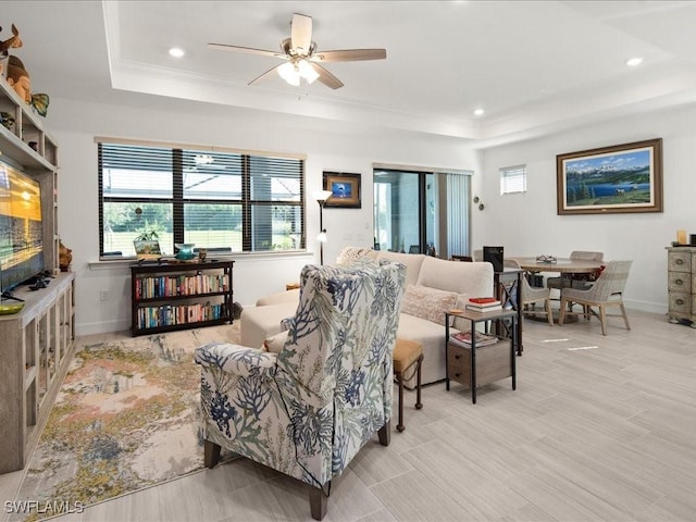 living room featuring ceiling fan, crown molding, and a tray ceiling