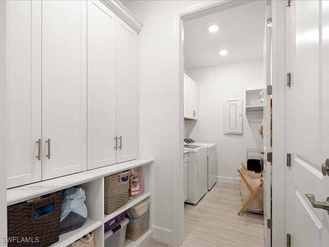 laundry area featuring washer and dryer, cabinets, light wood-type flooring, and electric panel