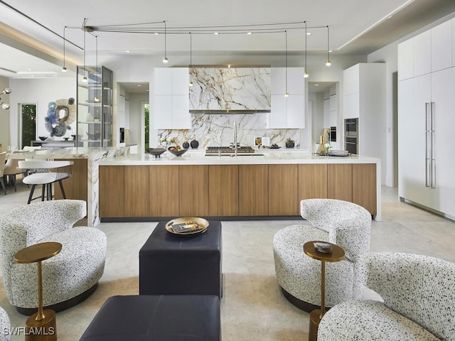 kitchen with a large island, paneled refrigerator, decorative light fixtures, and white cabinets