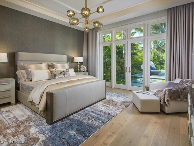 bedroom featuring multiple windows, access to exterior, a chandelier, and light hardwood / wood-style floors