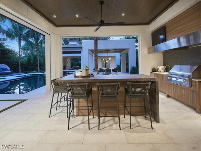 interior space featuring ceiling fan, a grill, exterior kitchen, and an outdoor bar