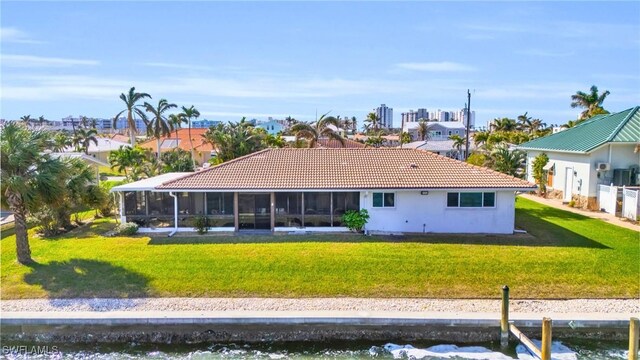 back of property with a lawn and a water view