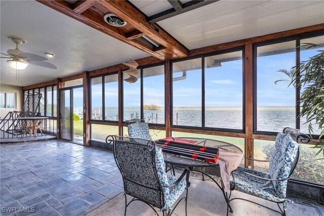 sunroom with beamed ceiling, a water view, ceiling fan, and a healthy amount of sunlight