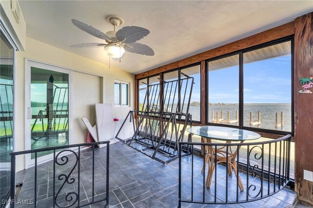 unfurnished sunroom with ceiling fan and a water view