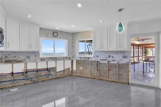 kitchen with pendant lighting, ceiling fan, decorative backsplash, and white cabinetry