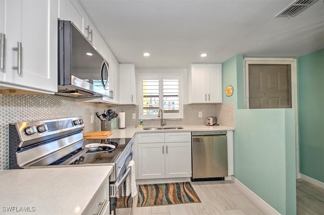 kitchen with backsplash, stainless steel appliances, white cabinetry, and sink