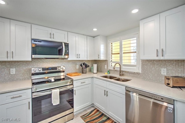 kitchen featuring backsplash, white cabinetry, sink, and appliances with stainless steel finishes